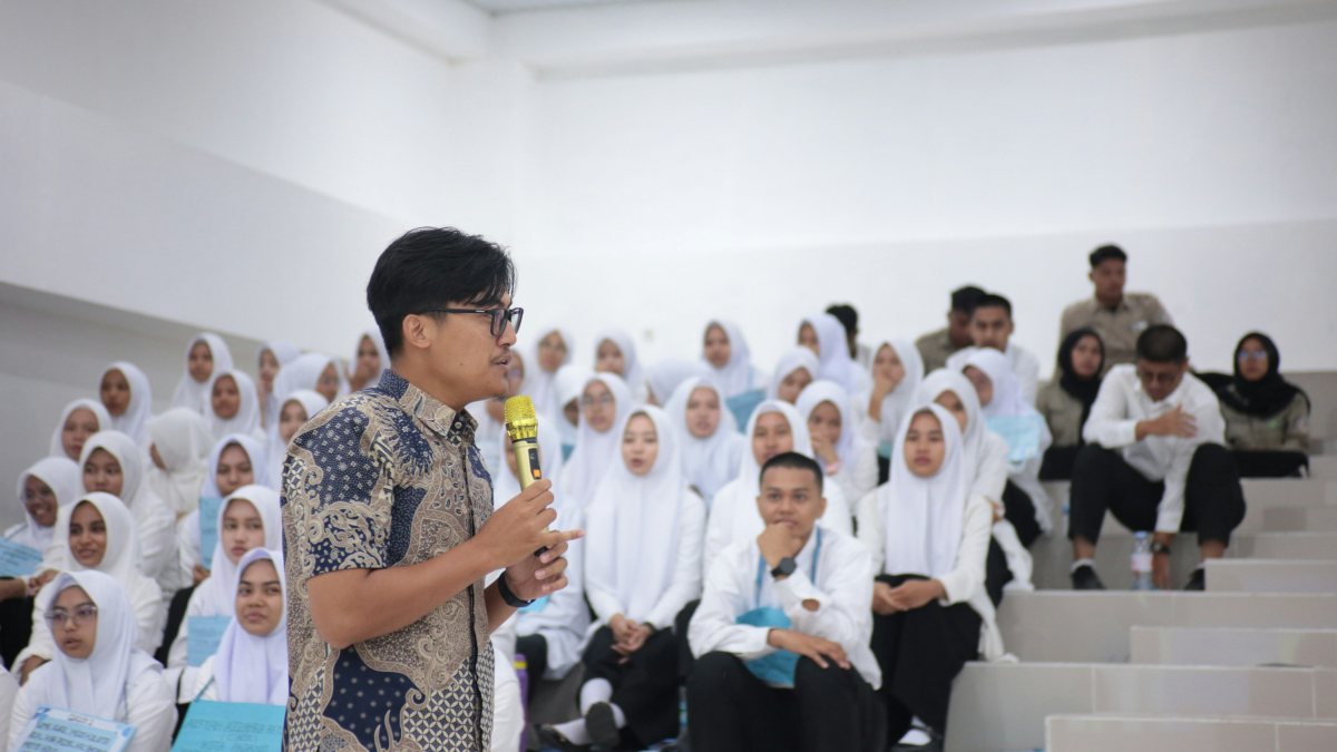 A speaker with a microphone leading a session for a hall of students